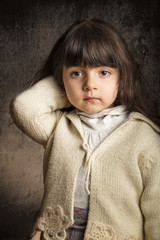 Small girl with classic pose in front of textured background