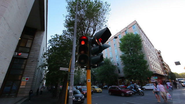 A corner stoplight stays a consistent red as people cross the street