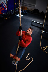 Athlete doing rope climb at gym