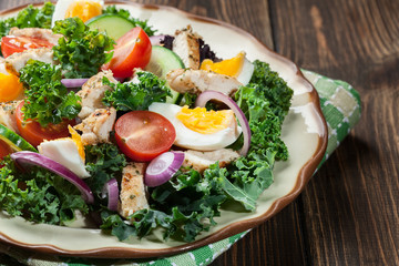 Fresh salad with chicken, tomatoes, eggs and lettuce on plate