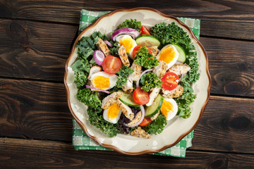 Fresh salad with chicken, tomatoes, eggs and lettuce on plate
