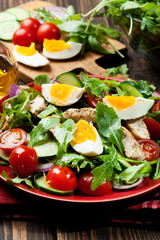 Fresh salad with chicken, tomatoes, eggs and arugula on plate