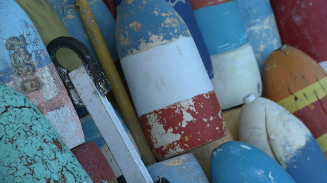 Close-up pan of striped fishing buoys stacked in Massachusetts.
