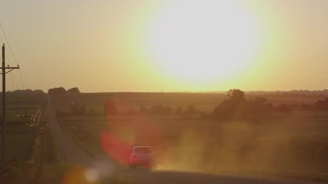 Static view of fields with the sun above the horizon, as truck drives by.