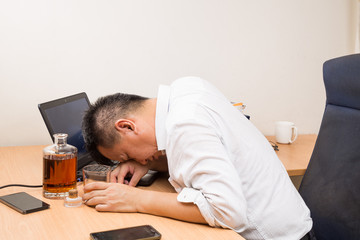 Depressed Asian business manager drunk on office desk