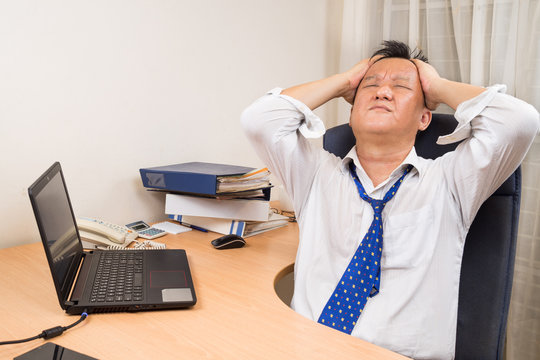 Frustrated And Stressful Asian Business Manager Behind Desk In Office