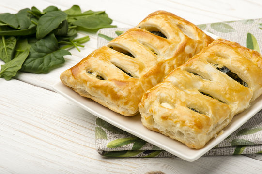 Puff pastry with spinach and feta on the wooden background.