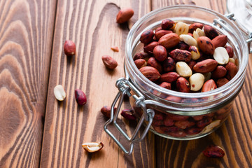 roasted peanuts in a glass jar on a wooden background