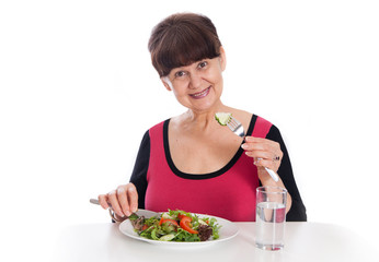 Obraz na płótnie Canvas Elderly good looking woman eating green salad. Healthy life style concept