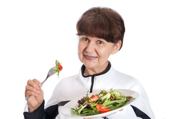 Elderly woman in sport costume eating green salad. Healthy life style concept