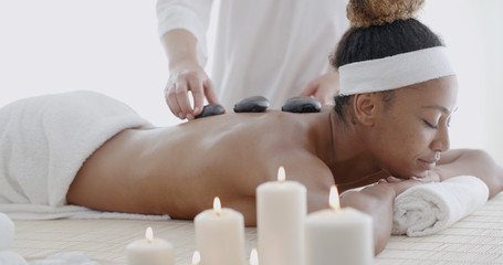 Obraz na płótnie Canvas Young woman getting hot stone massage in spa salon