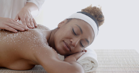 Female getting a salt scrub beauty treatment in the health spa