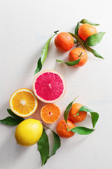 Fresh citrus fruits with leaves on table
