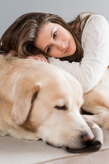 Woman laying on her dog and smiling