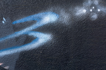 Detail of a graffiti art on a wall. Wall painted in different colors. Abstract dark blue background.