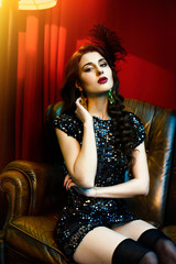 beautiful retro stiled woman sitting in sofa on a red background