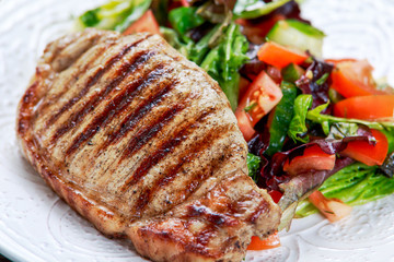 Grilled pork meat and vegetables on plate
