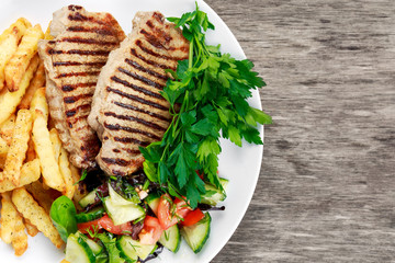 Grilled pork meat  with fried potatoes and vegetables