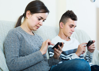  brunette and teenager looking at screens of smartphones