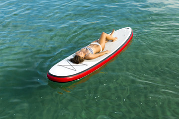 Woman relaxing over a paddle surfboard