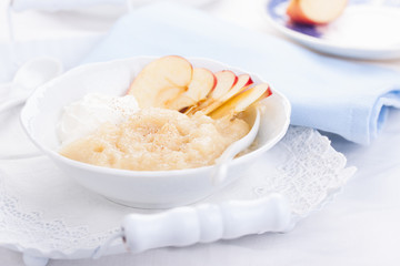 Apple puree dessert with cream and fresh apples in a white bowl on a white tea-tray. selective focus..
