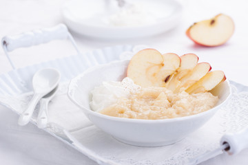 Apple puree dessert with cream and fresh apples in a white bowl on a white tea-tray. selective focus