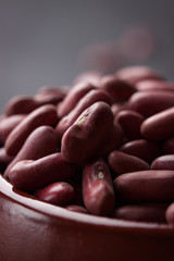 Red kidney bean in a red ceramic bowl on a black stone background
