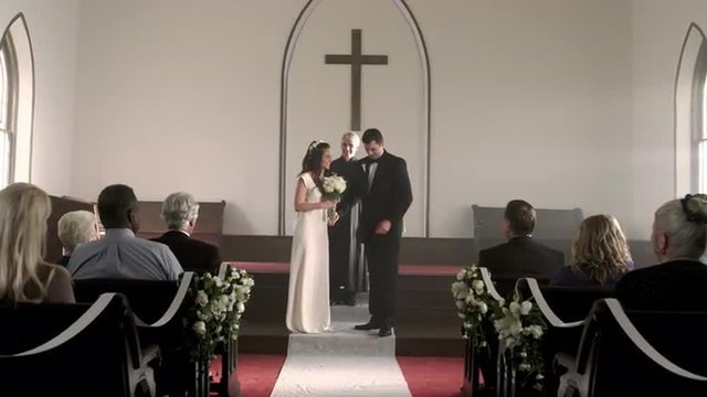 Newlywed couple kisses and walks down the aisle.