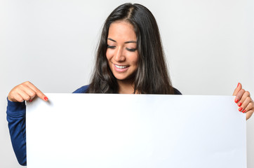 Fototapeta premium Smiling woman pointing to a blank white sign