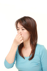 Japanese woman holding her nose because of a bad smell