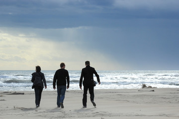 groupe de trois personnes marchant vers la mer