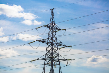 Electricity pylon silhouetted against blue sky background. High voltage tower.