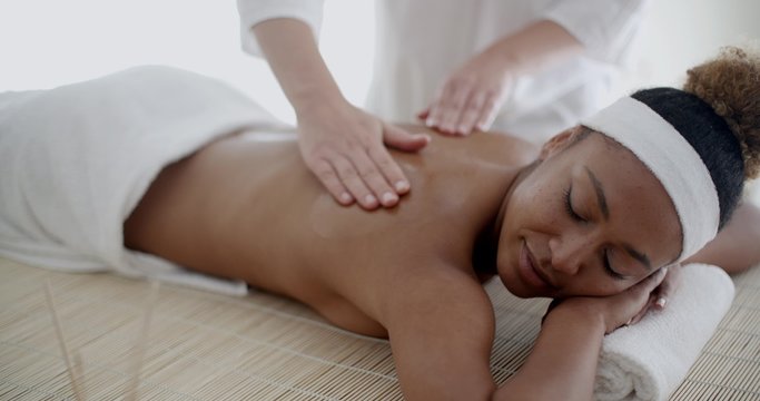 Female therapist's hands doing back massage on woman