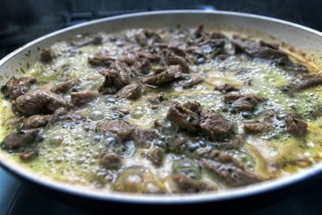 Strips of turkey meat in pan being cooked in wine