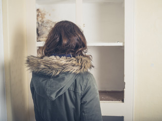 Woman in coat looking at old cupboard