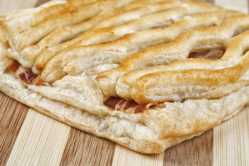 Close up shot of danish pastry with crispy grilled bacon. Studio shot on wooden table.