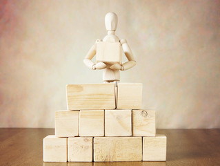 Man building a wall of big blocks. Conceptual image with wooden puppet