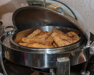 Shiny chafing dish keeps the crispy egg rolls warm. 
