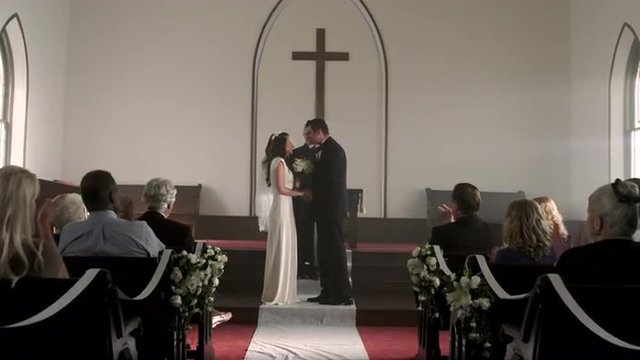 Shot of a newlywed couple kissing and walking down the aisle.