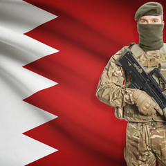 Fototapeta premium Soldier with machine gun and flag on background - Bahrain