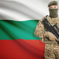 Fototapeta premium Soldier with machine gun and flag on background - Bulgaria