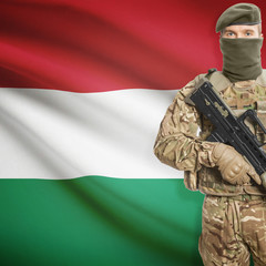 Fototapeta premium Soldier with machine gun and flag on background - Hungary