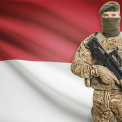 Fototapeta premium Soldier with machine gun and flag on background - Indonesia
