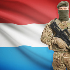 Fototapeta premium Soldier with machine gun and flag on background - Luxembourg