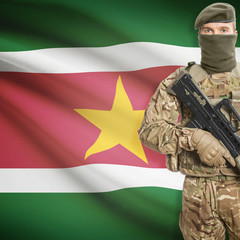 Fototapeta premium Soldier with machine gun and flag on background - Suriname