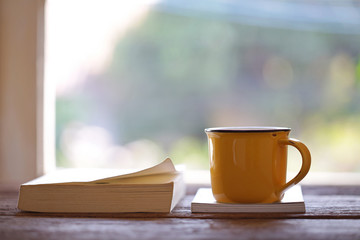 Notebook and yellow cup on wooden table