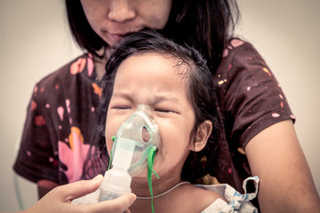little girl crying while getting in inhaler mask in hospital