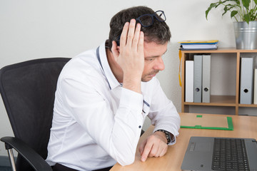 A business man is working worried on a computer.