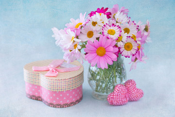 Daisy flowers and  box with a gift on a blue background with а texture .