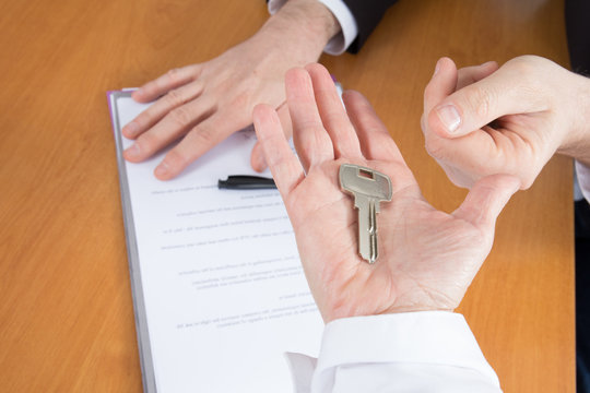 Real estate agent gives house keys to client signing contract